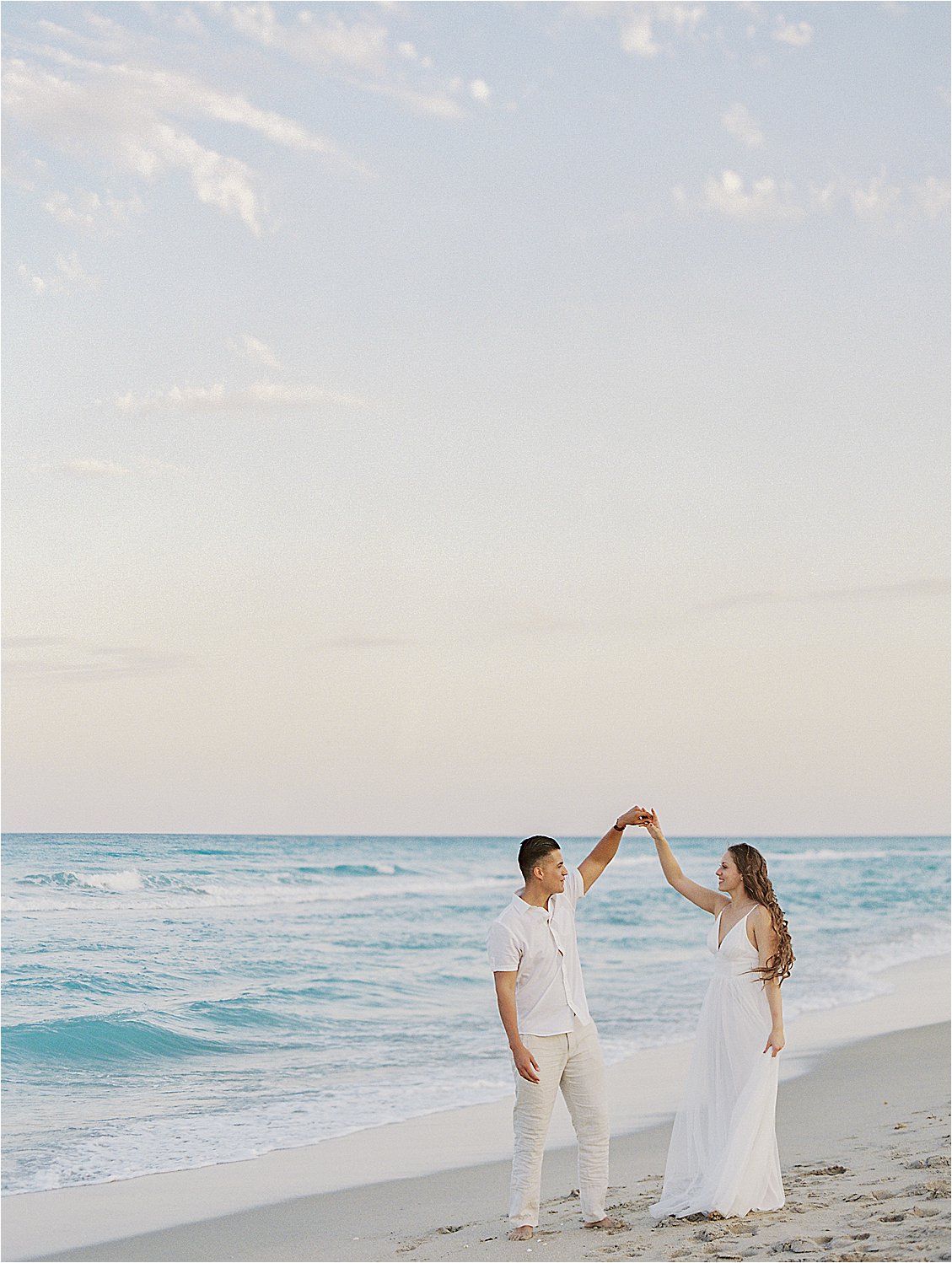 Engaged Couple dancing by the beach at Palm Beach Engagement Session with film wedding photographer, Renee Hollingshead