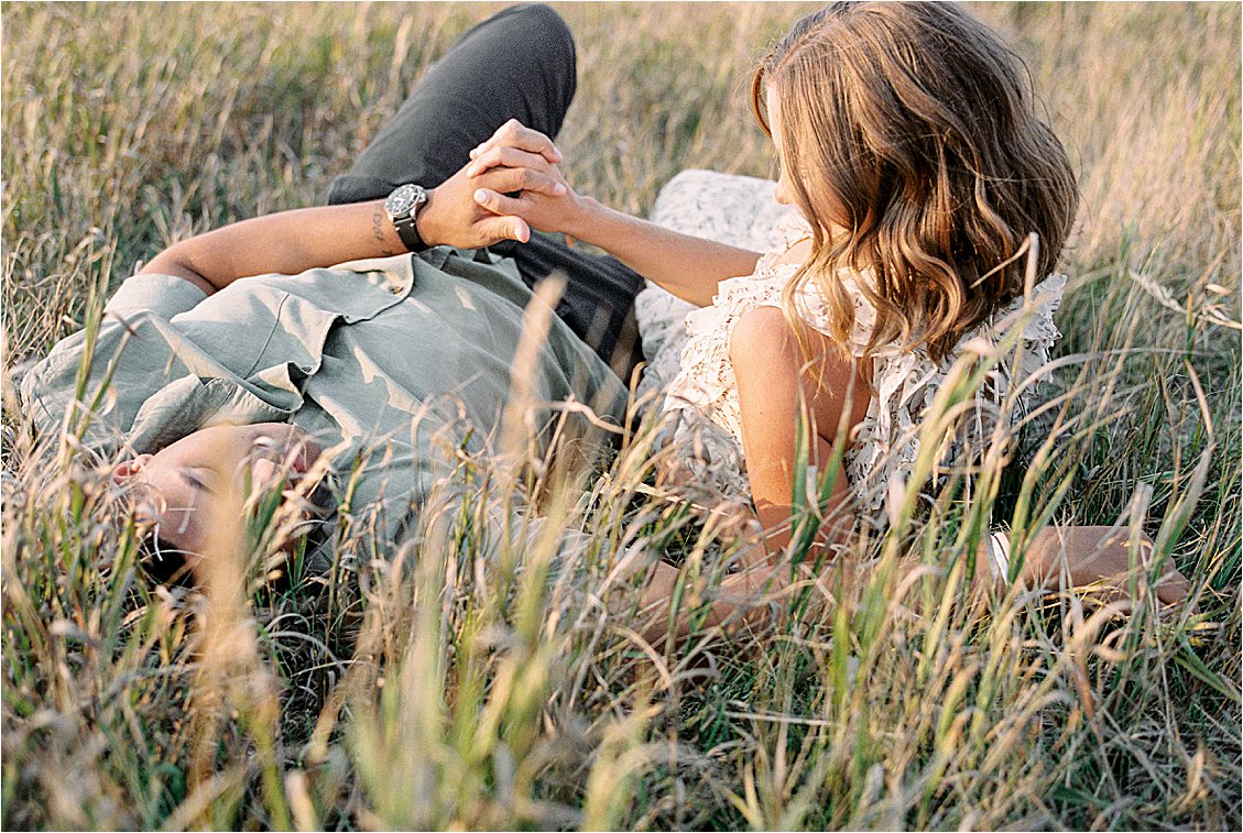 Couple holding hands in the grass at summer engagement session with film wedding photographer Renee Hollingshead