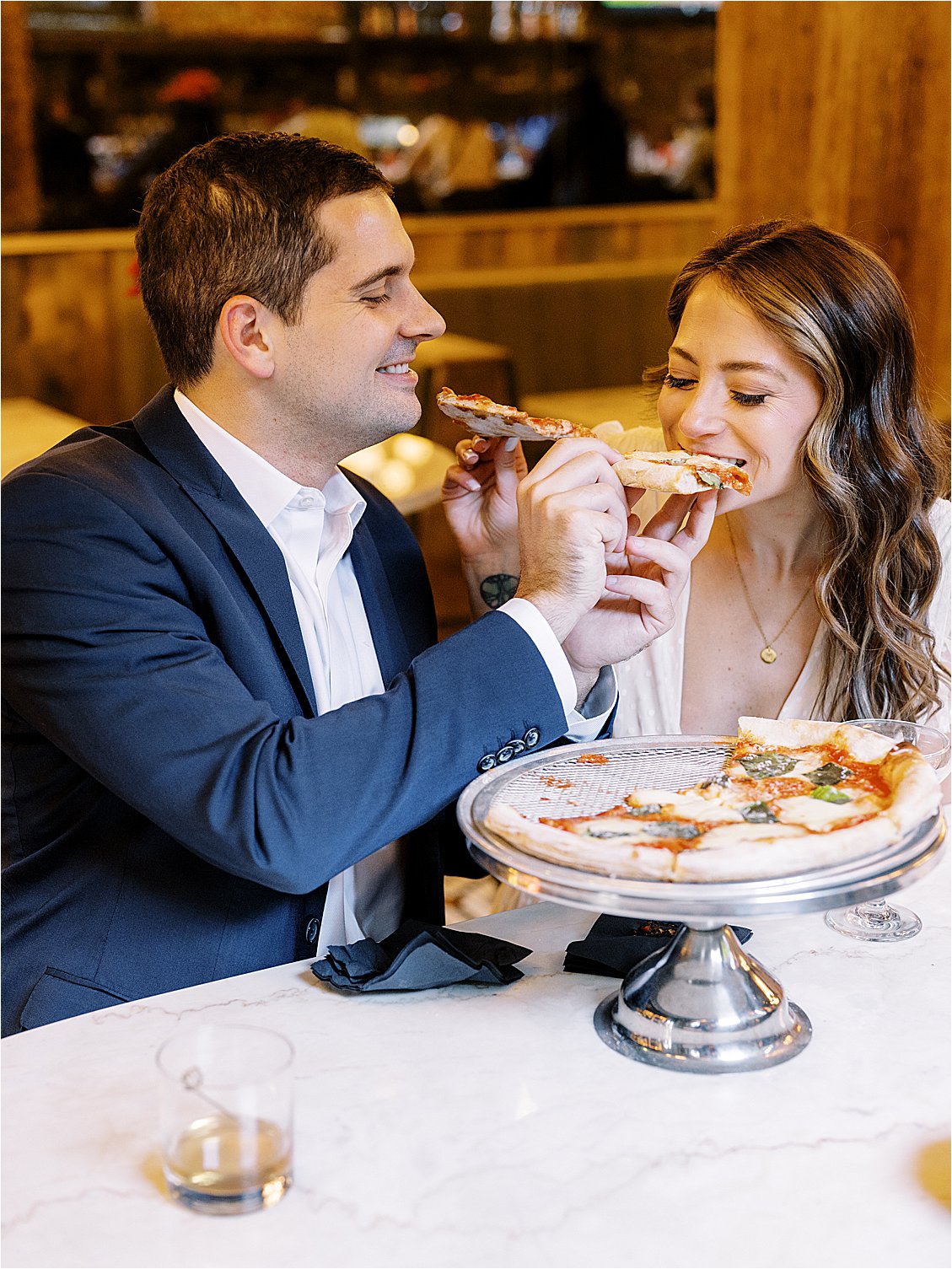 Couple shares a pizza during engagement session at Italian Disco in Fells Point Baltimore, Maryland