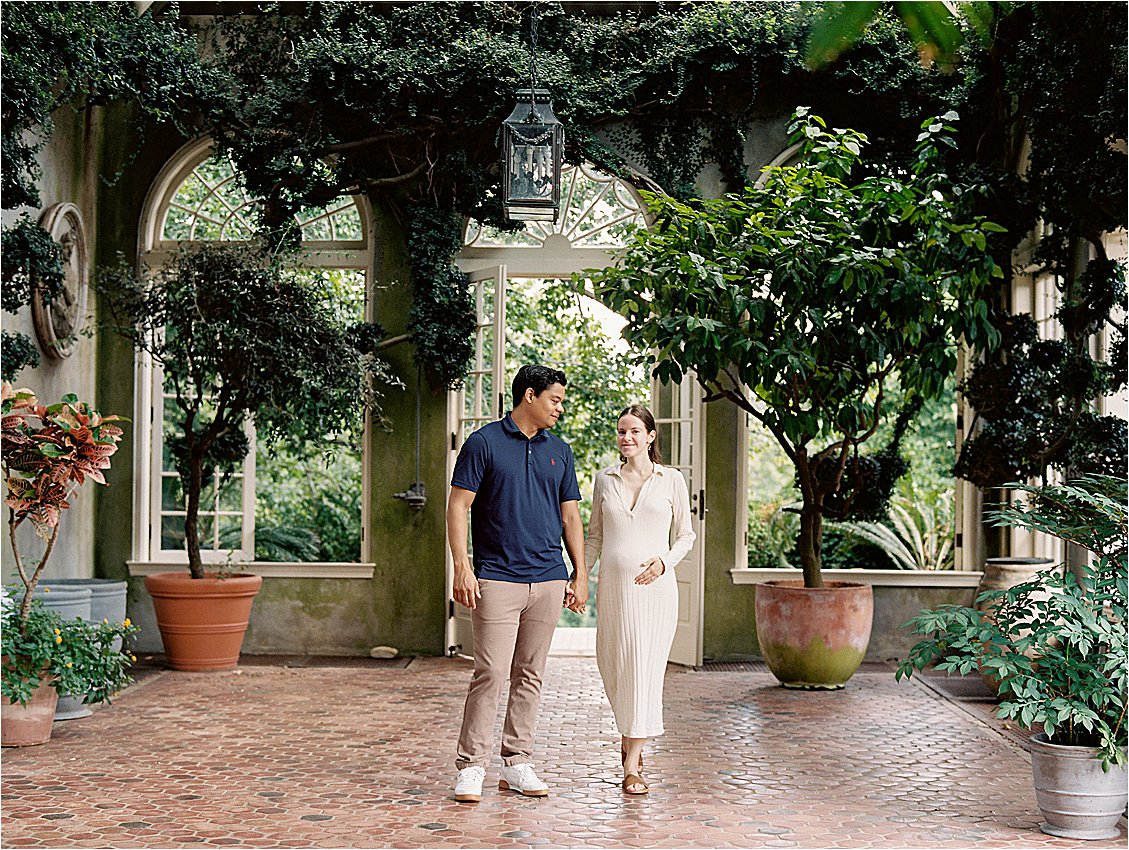 Expecting couple walks through Atrium in Washington DC garden