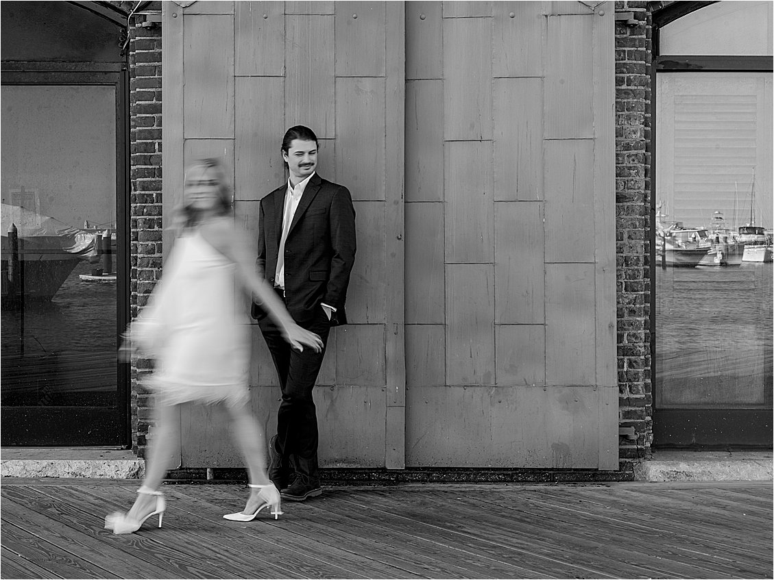 Black and white slow shutter image of bride walking in front of groom 