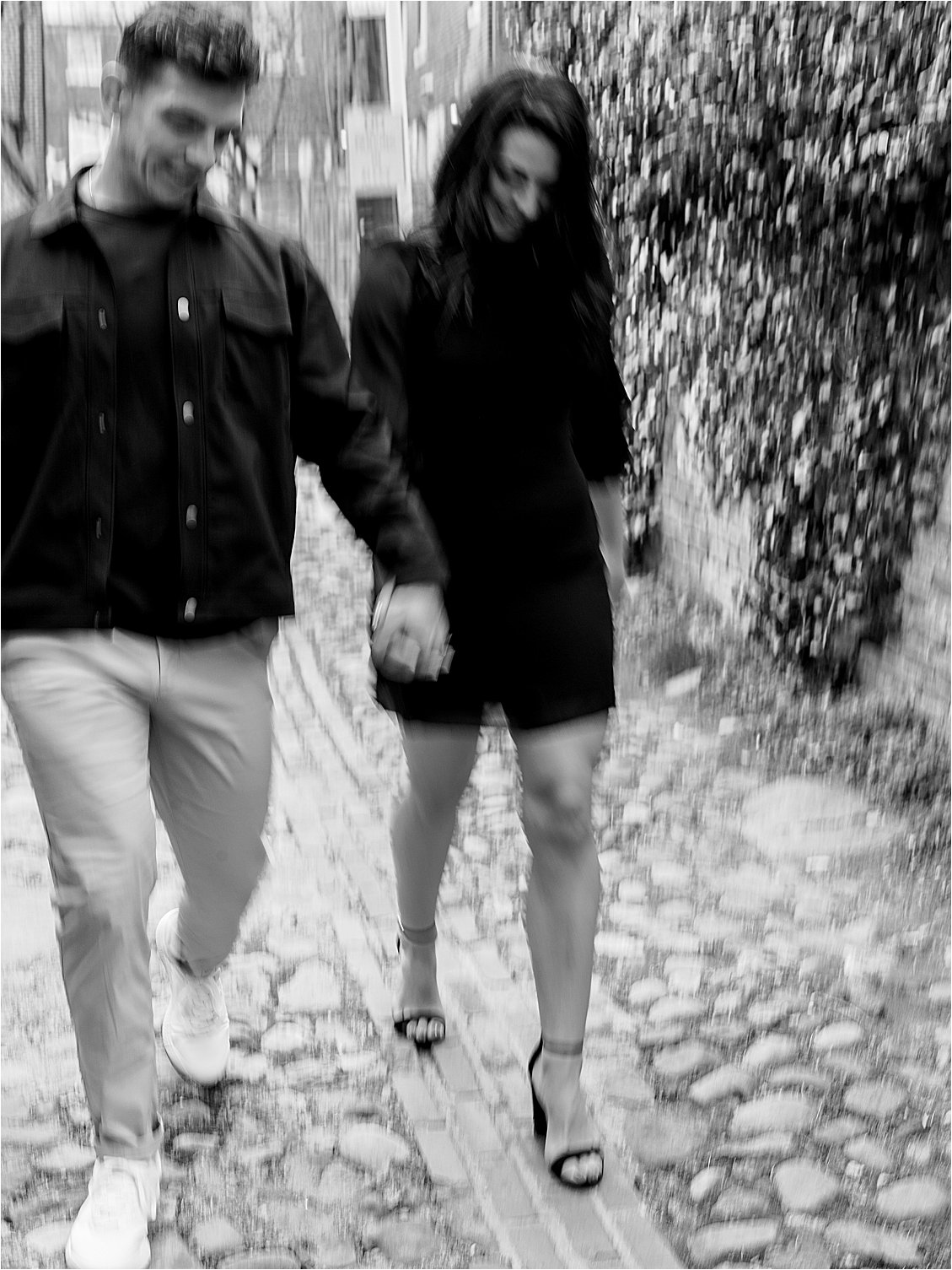 Motion Blur Slow Shutter black and white image of couple walking on cobblestone in Old Town Alexandria Engagement SEssion