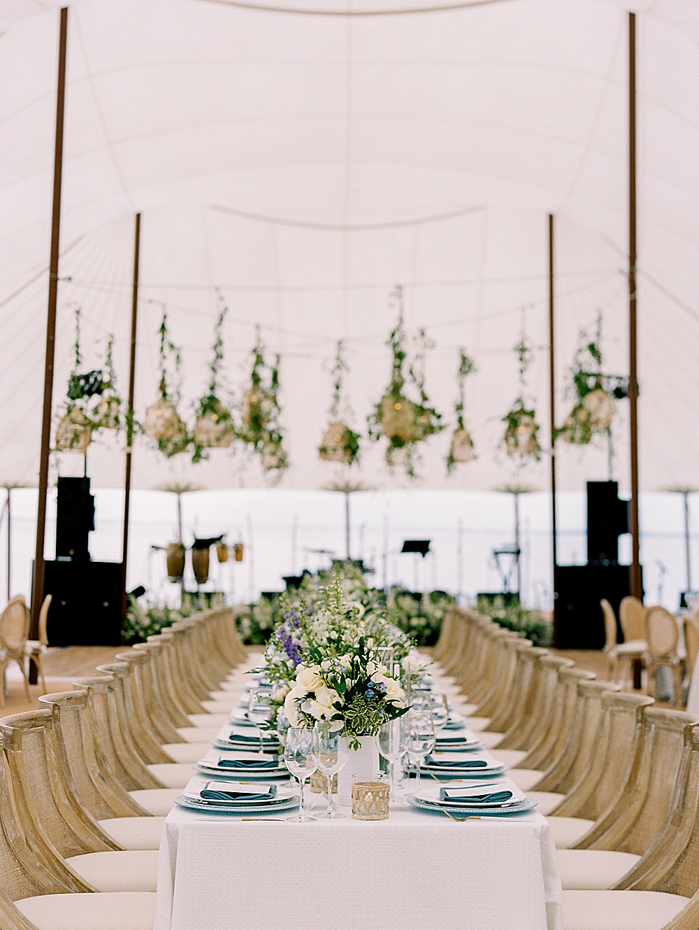 Long kings table in sail cloth tented waterfront wedding by destination film wedding photographer Renee Hollingshead