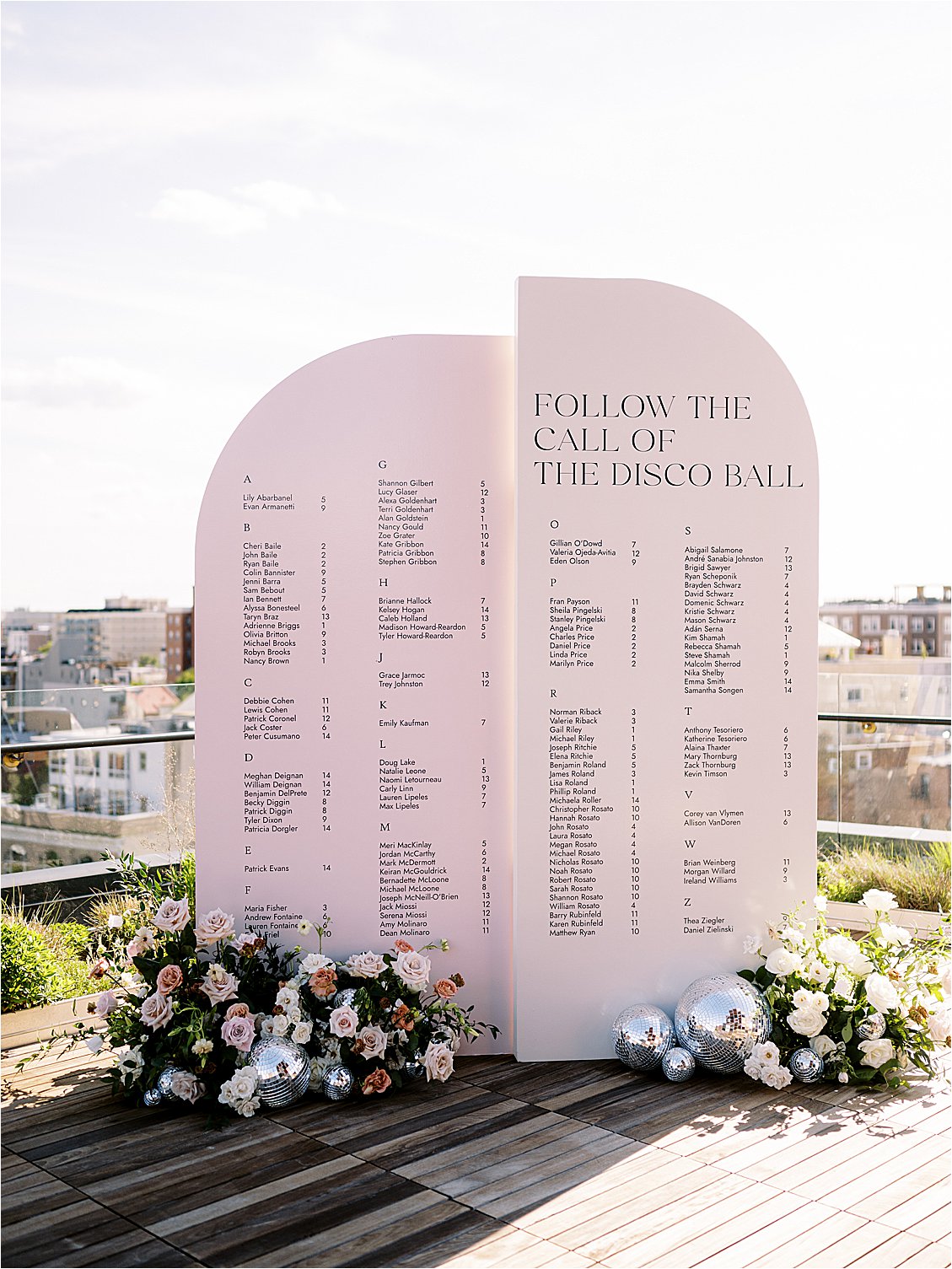 Follow the Call of the Disco Ball Pink Arched Escort Display with disco balls and florals at a rooftop wedding in DC