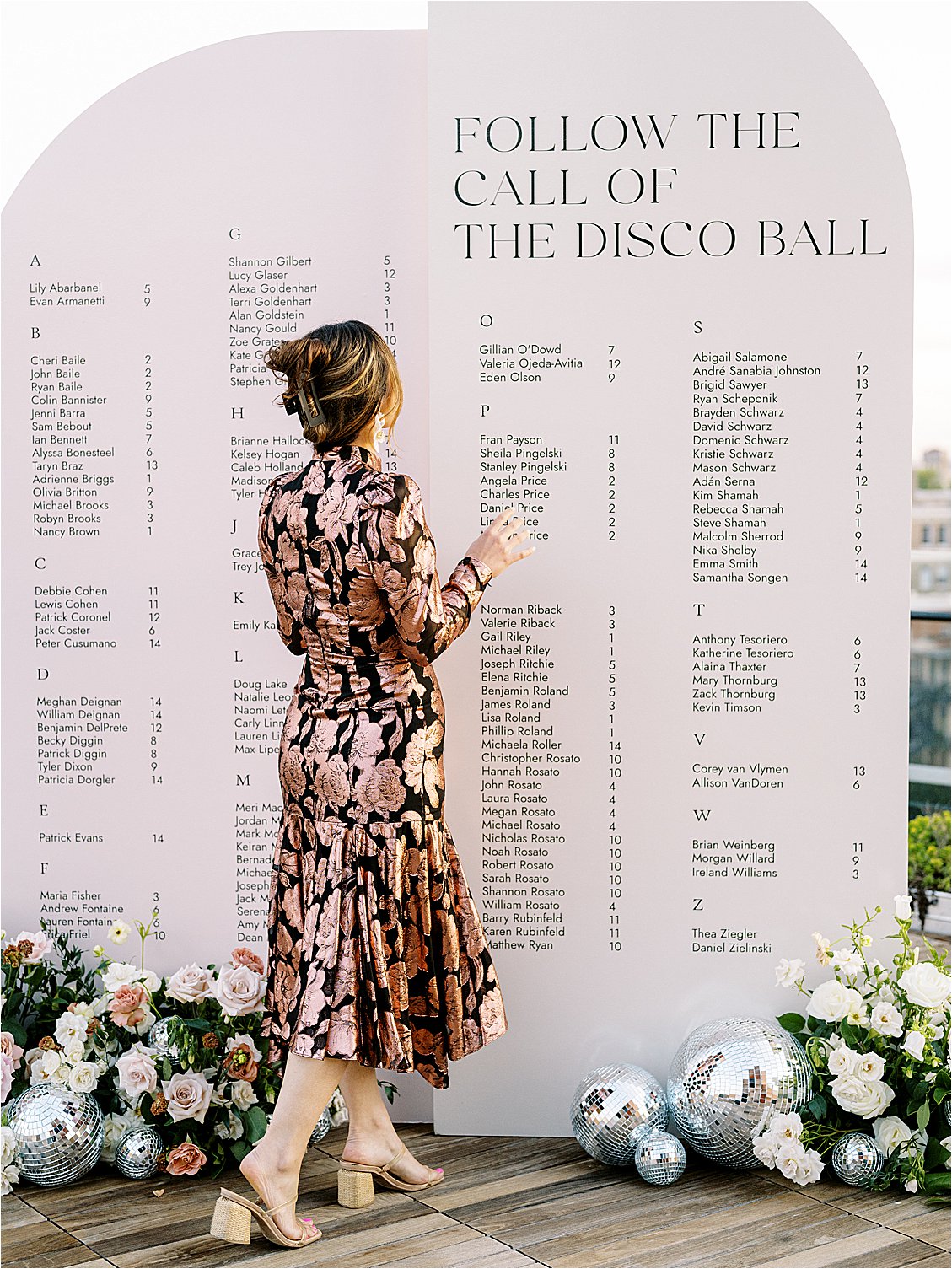 Modern and chic escort display with floral and disco ball installation at rooftop wedding