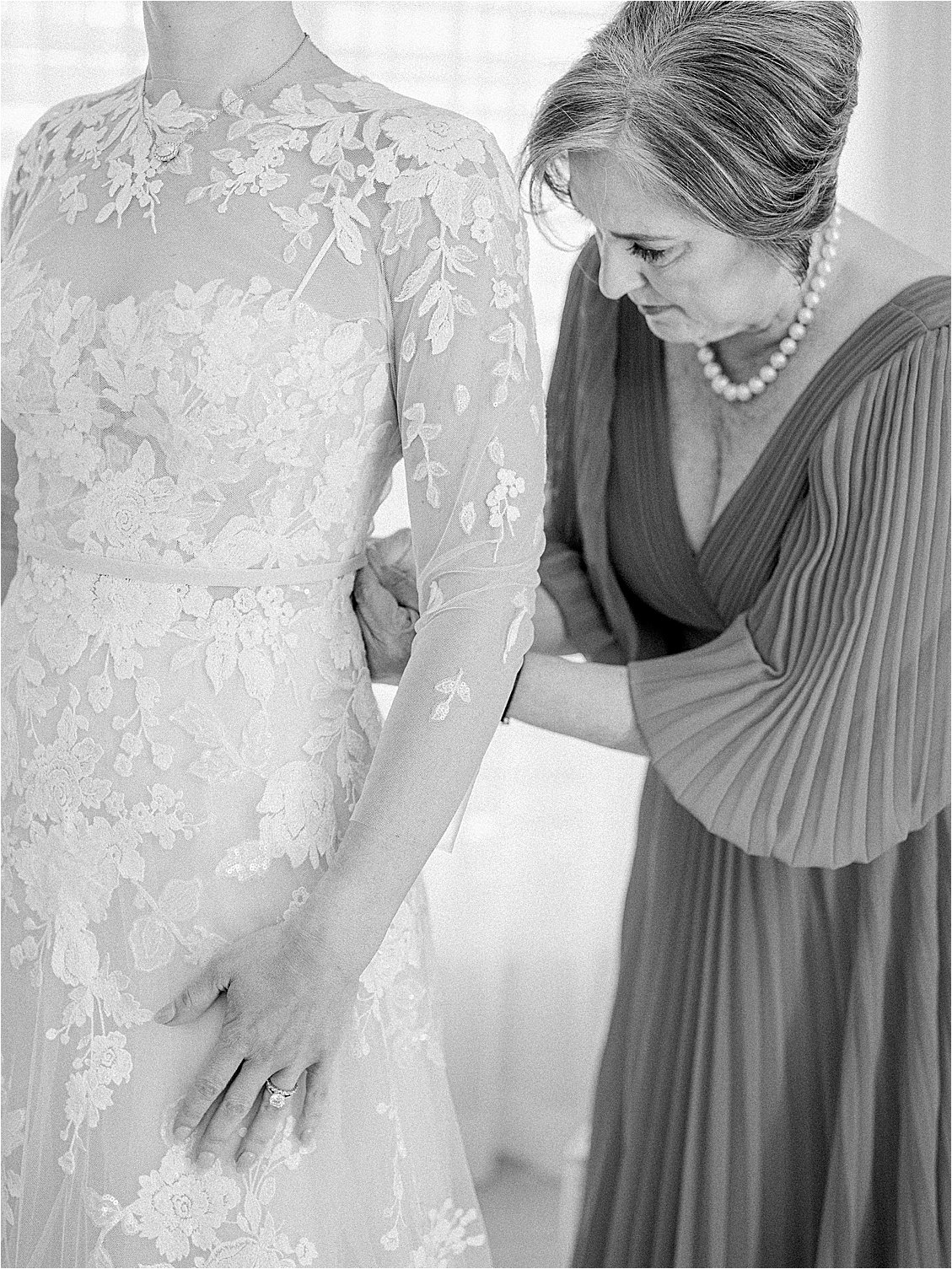 Mother of the bride dressing daughter before she walks down the aisle