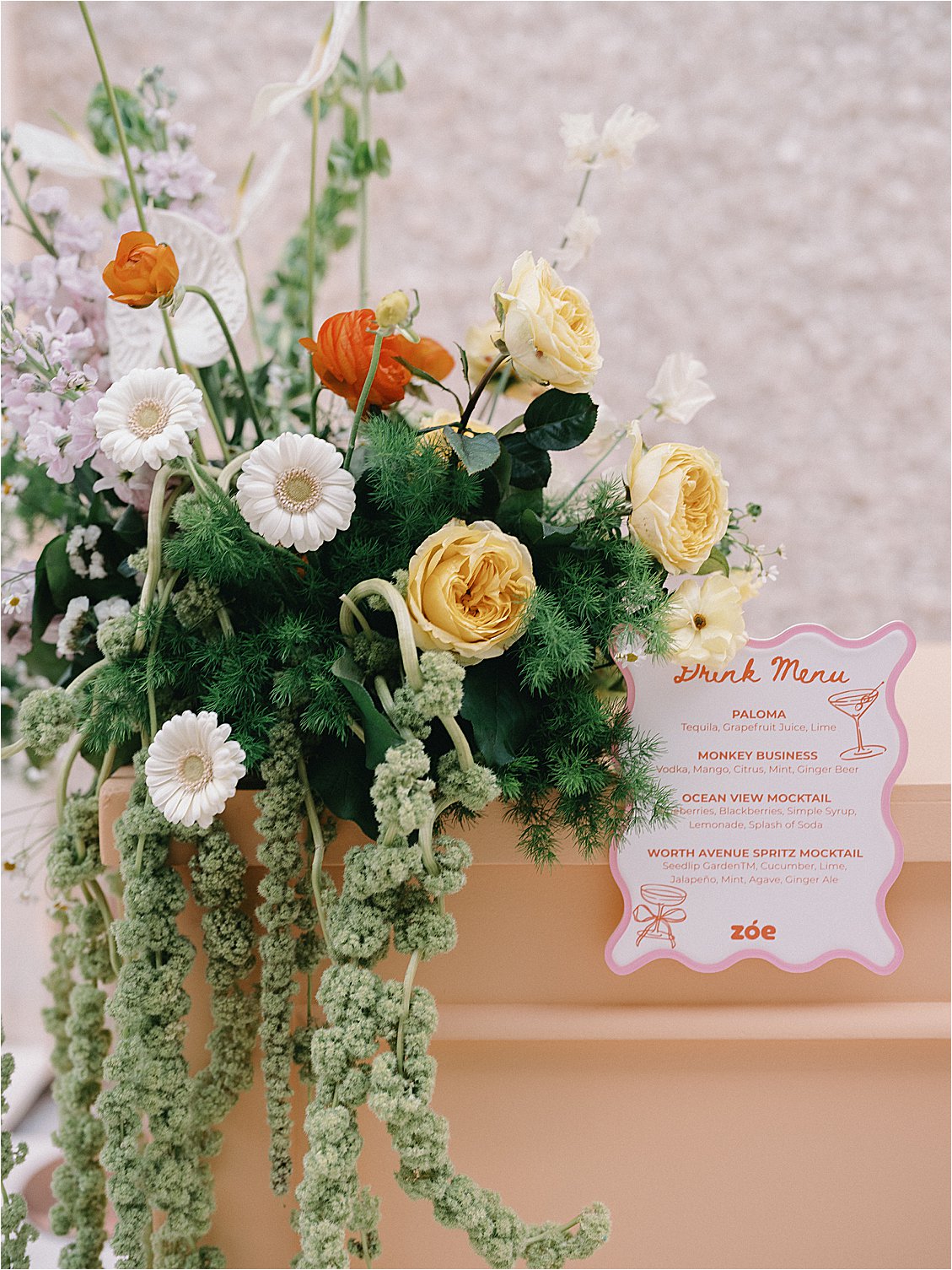 Close-up of Zoe Strollers branded drink menu card nestled within the citrus floral arrangement on the peach bar at The Colony Hotel Palm Beach East Garden corporate dinner 