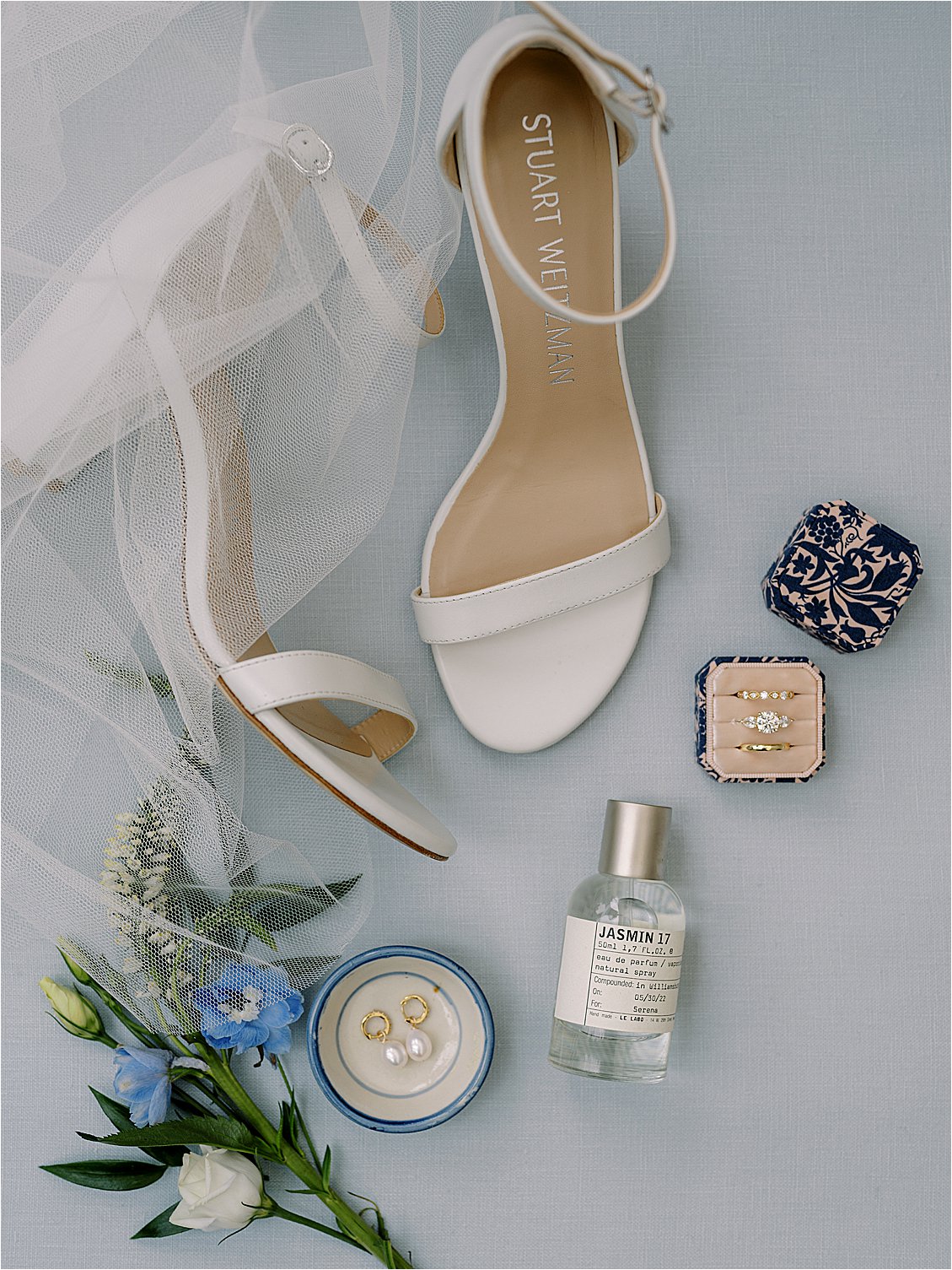 Bridal details with Stuart Weitzman heels, rings, perfume, and blue flowers at Eastern Shore waterfront estate wedding