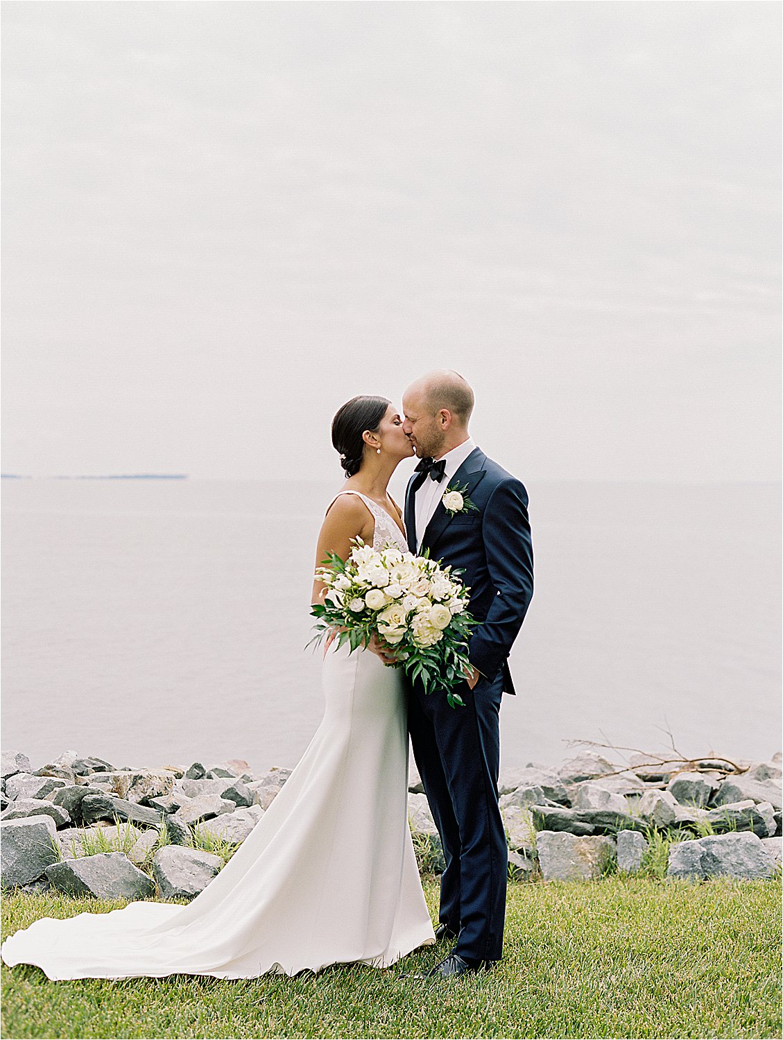 Bride and groom kissing by the Chesapeake Bay during elegant Eastern Shore waterfront wedding