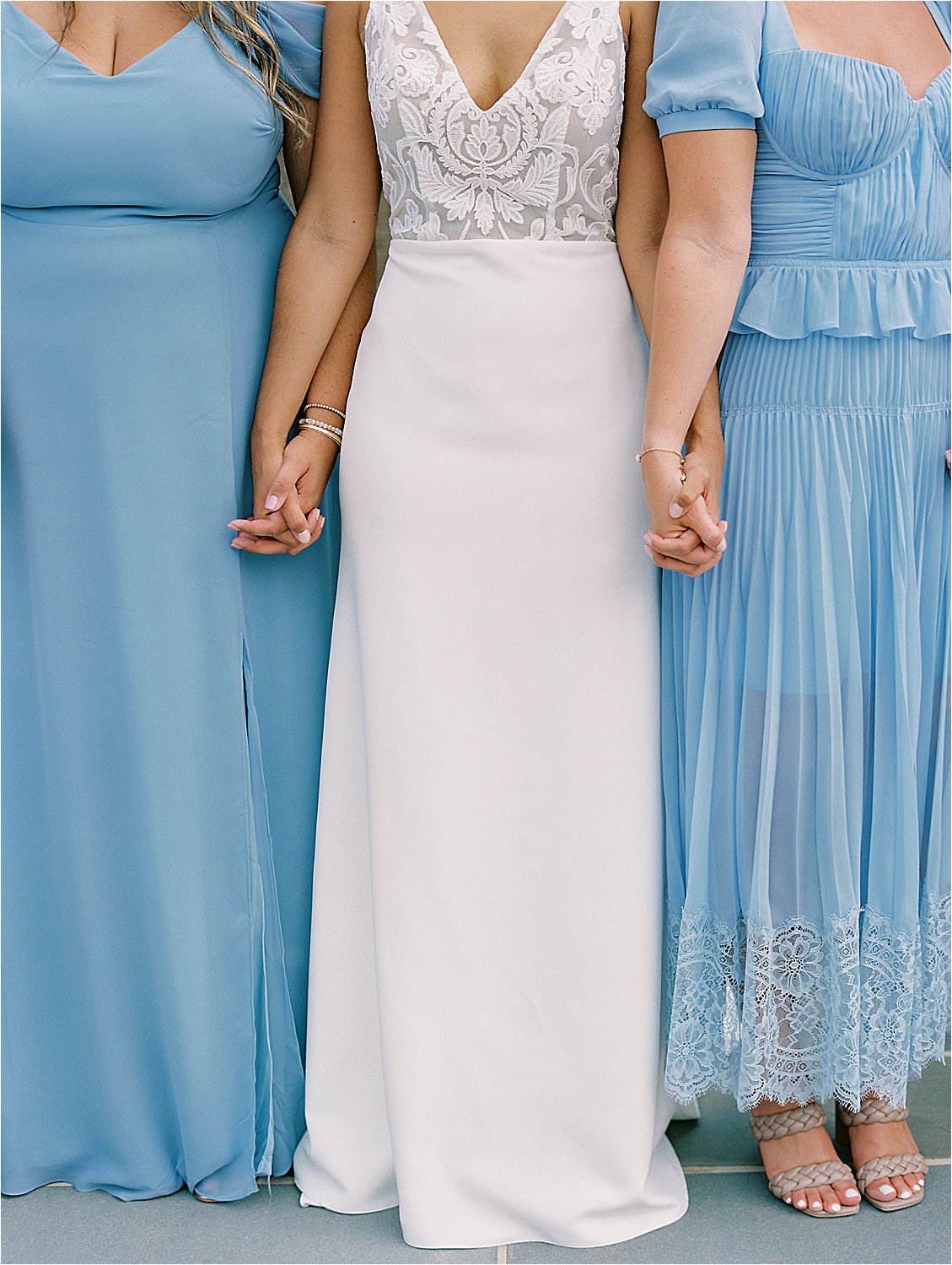 Bride and bridesmaids holding hands in blue dresses at elegant Eastern Shore waterfront wedding