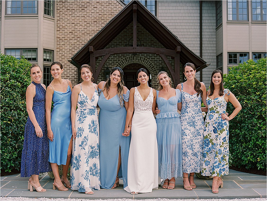 Bride and bridesmaids holding hands in blue dresses at elegant Eastern Shore waterfront wedding