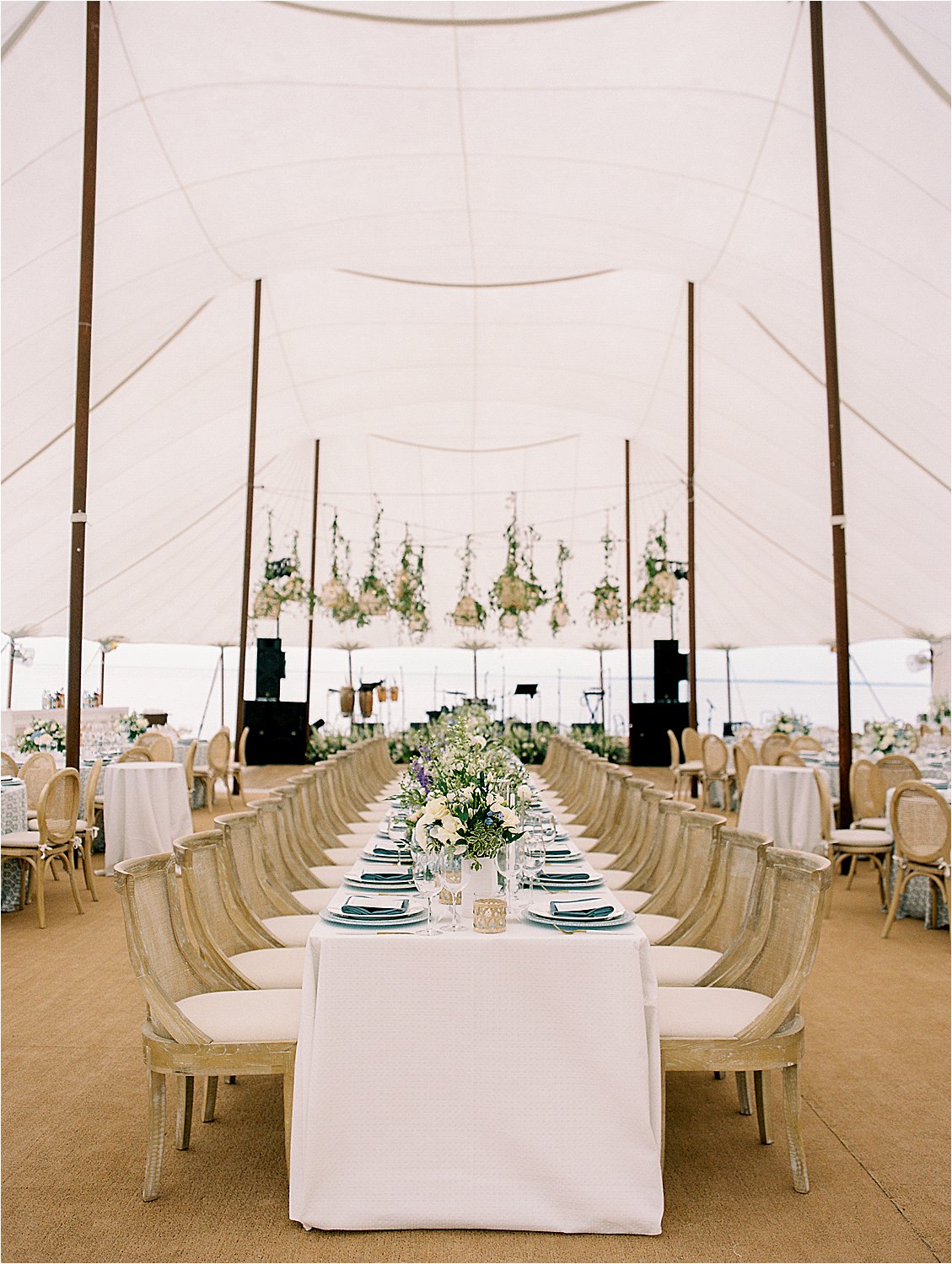 Elegant sailcloth tent reception with long king table and greenery installation at Oxford Maryland waterfront estate wedding