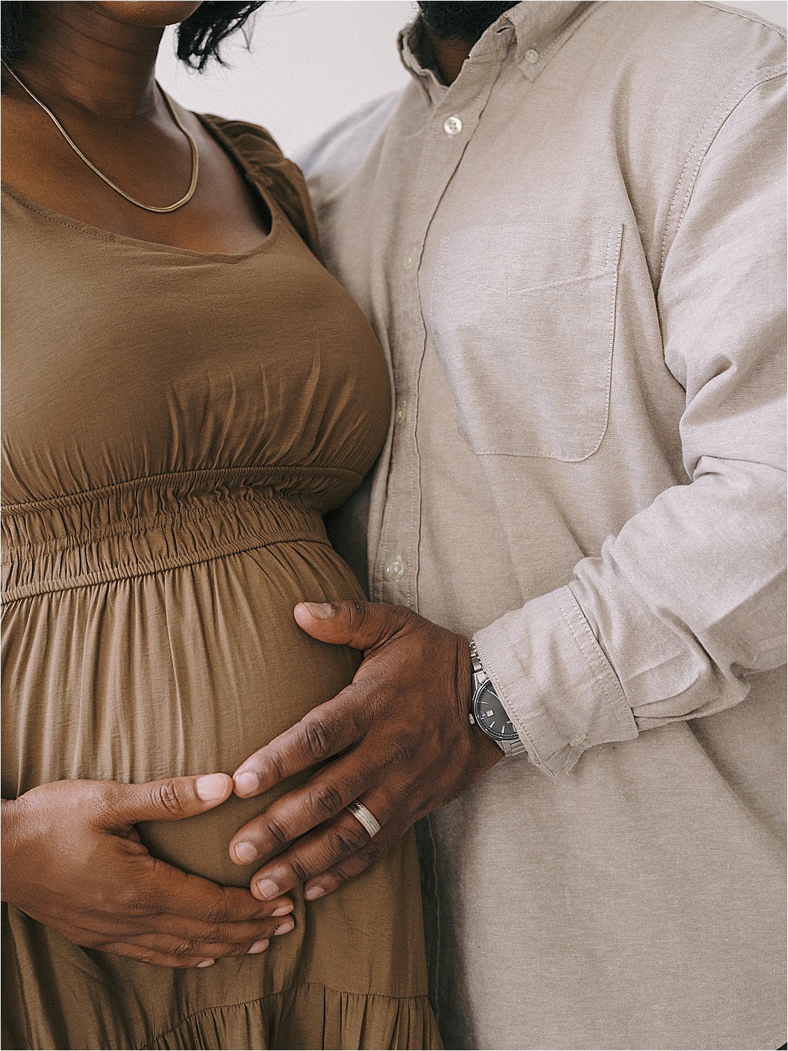 Close up of expecting couple's hands cradling baby bump during studio maternity session in Annapolis Maryland, film photography by Renee Hollingshead