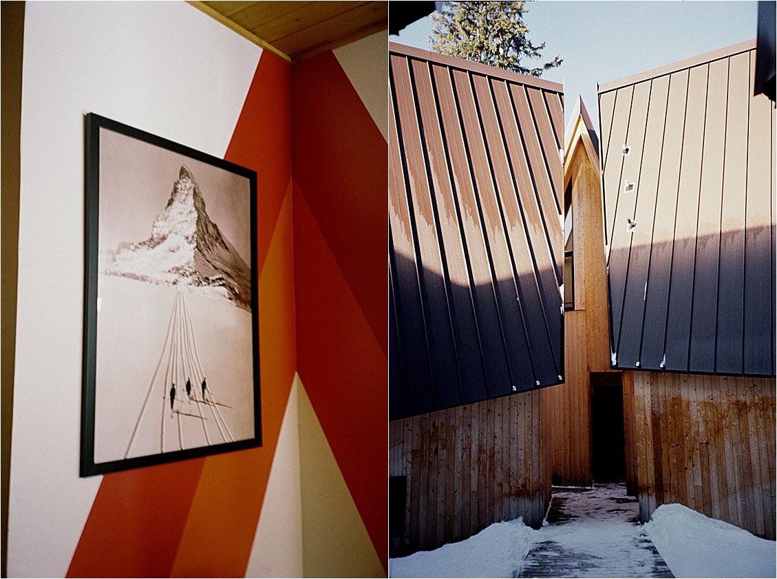 Interior of A-Frame Club Winter Park Colorado featuring a framed vintage ski mountain photograph on a bold geometric painted wall, alongside the dramatic A-frame exterior roofline at golden hour. Film photo by Renee Hollingshead on Kodak Portra 400.