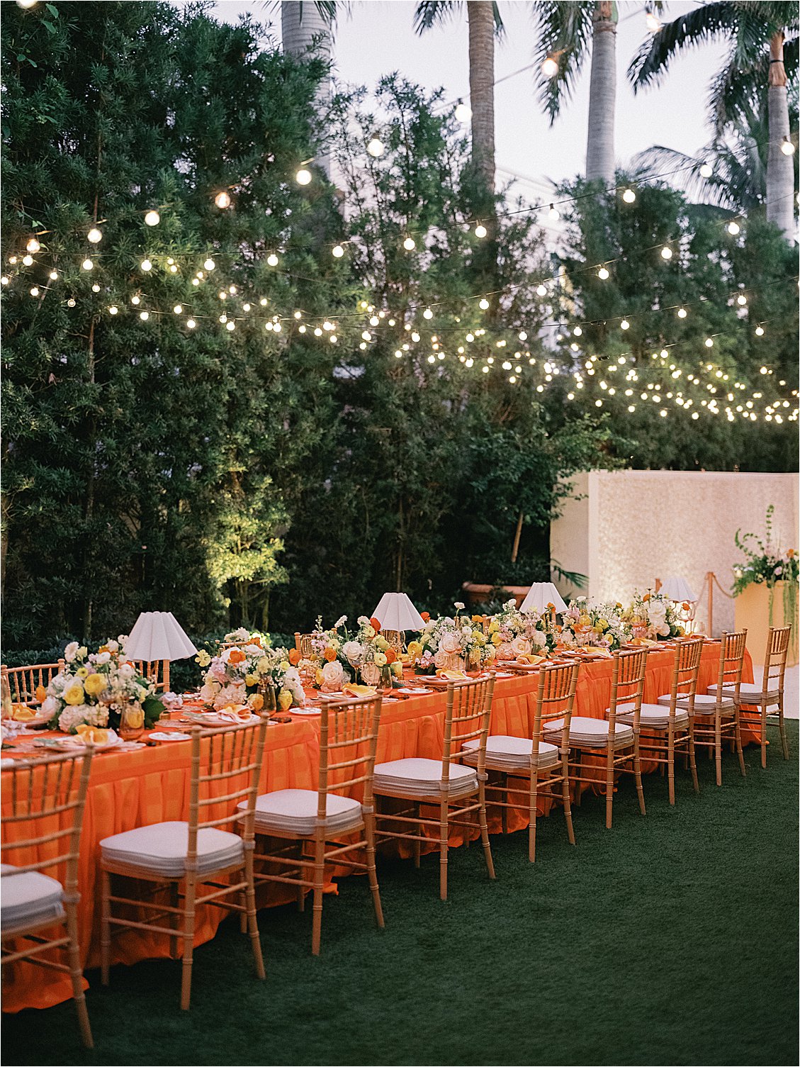 Evening view of the full corporate dinner table set for guests under café string lights in The Colony Hotel East Garden, Palm Beach, styled by Gramercy & Grace for the Zoe Strollers retreat, film photography by Renee Hollingshead 