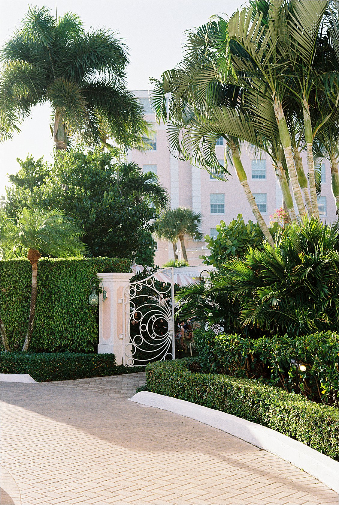 The Colony Hotel Palm Beach brick garden path leading to the ornate iron East Garden gate surrounded by manicured hedges and tall palm trees, photographed on film
