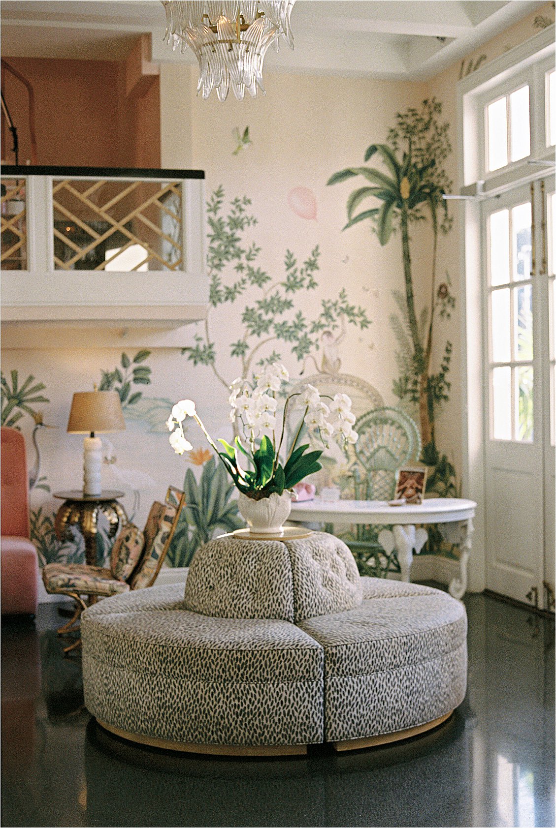 The Colony Hotel Palm Beach lobby interior featuring hand-painted tropical mural wallpaper, white orchids, crystal chandelier, and curved ottomans, photographed on film