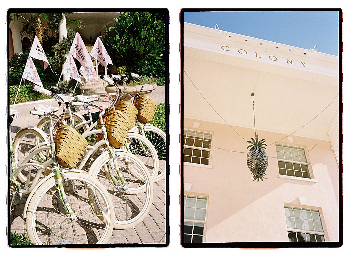 The Colony Hotel Palm Beach Palm Royale Bikes and Pineapple Chandelier Facade Alt Text: Diptych film photograph of white cruiser bikes with wicker baskets and Palm Royale flags alongside the Colony Hotel blush pink facade with hanging pineapple chandelier against a blue sky