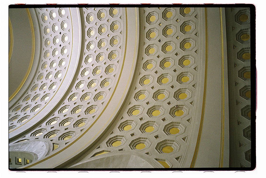 Close-up film photograph of the ornate gold and white coffered ceiling inside Union Station in Washington DC, with geometric octagonal patterns and warm ambient light. 