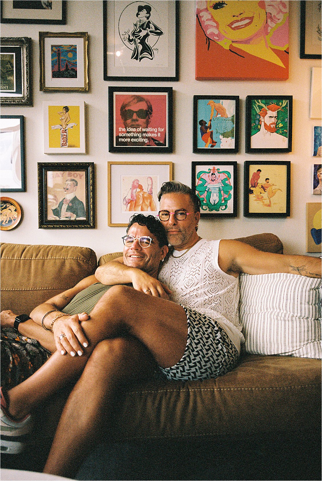 LGBTQ+ couple relaxed together on couch with bold colorful gallery wall behind them, Washington DC film portrait photographer, Kodak Portra 400