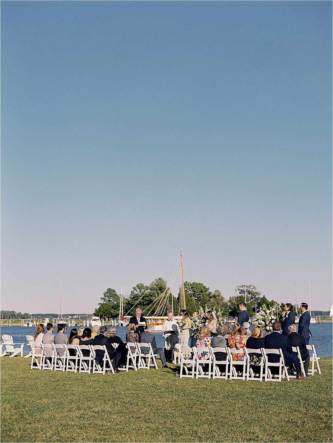 Outdoor waterfront wedding ceremony on the lawn at Inn at Perry Cabin with sailboats on the Miles River, captured on film by Renee Hollingshead Photography
