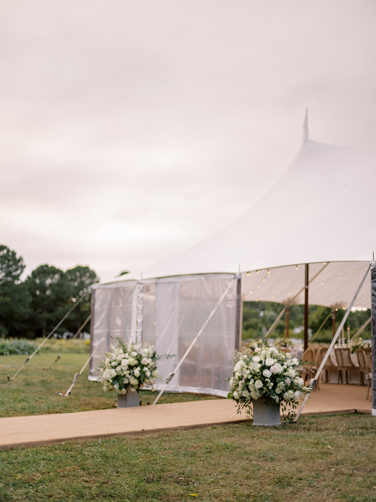 Sailcloth tent wedding reception entrance with white floral arrangements on a rainy Inn at Perry Cabin, St. Michaels Maryland wedding day