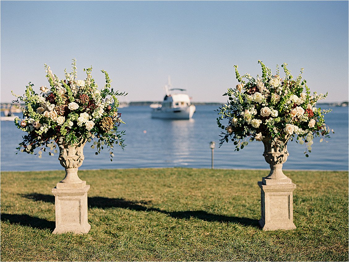 Lush floral ceremony urns on the waterfront lawn at Inn at Perry Cabin with sailboat on the Miles River, St. Michaels Maryland