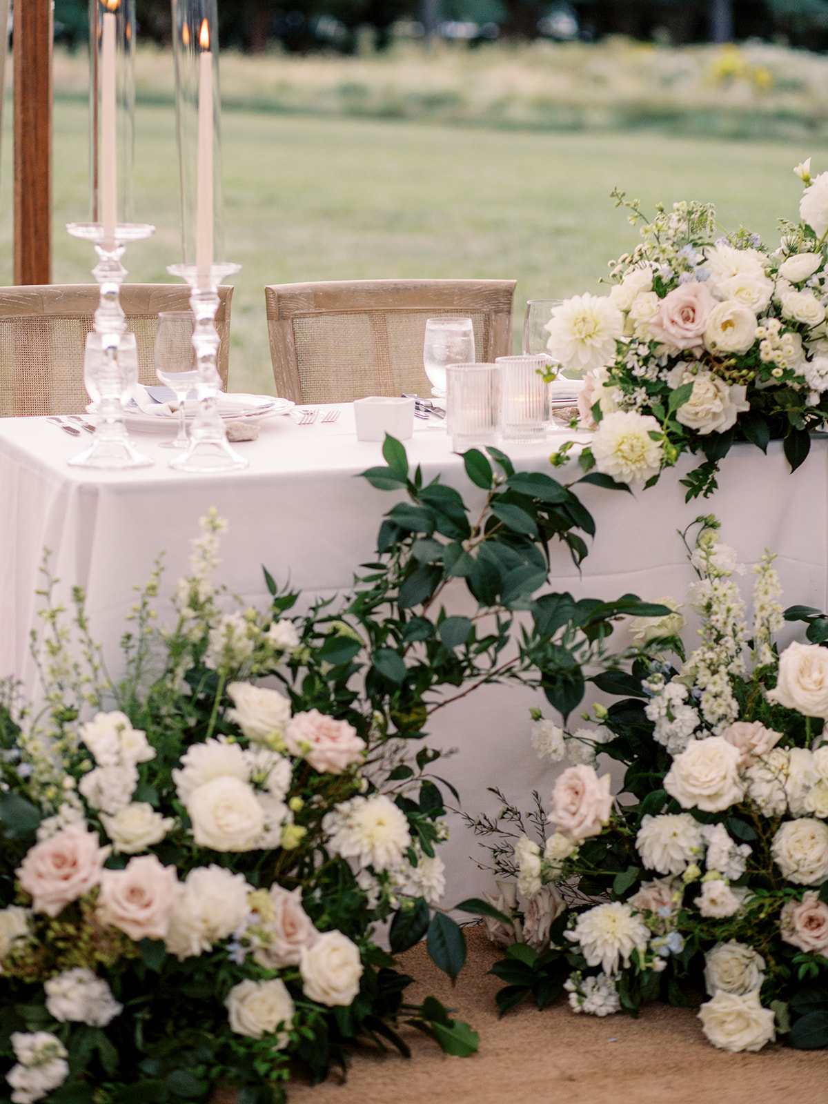 Lush white and blush floral arrangements at sweetheart table inside sailcloth tent at Inn at Perry Cabin wedding