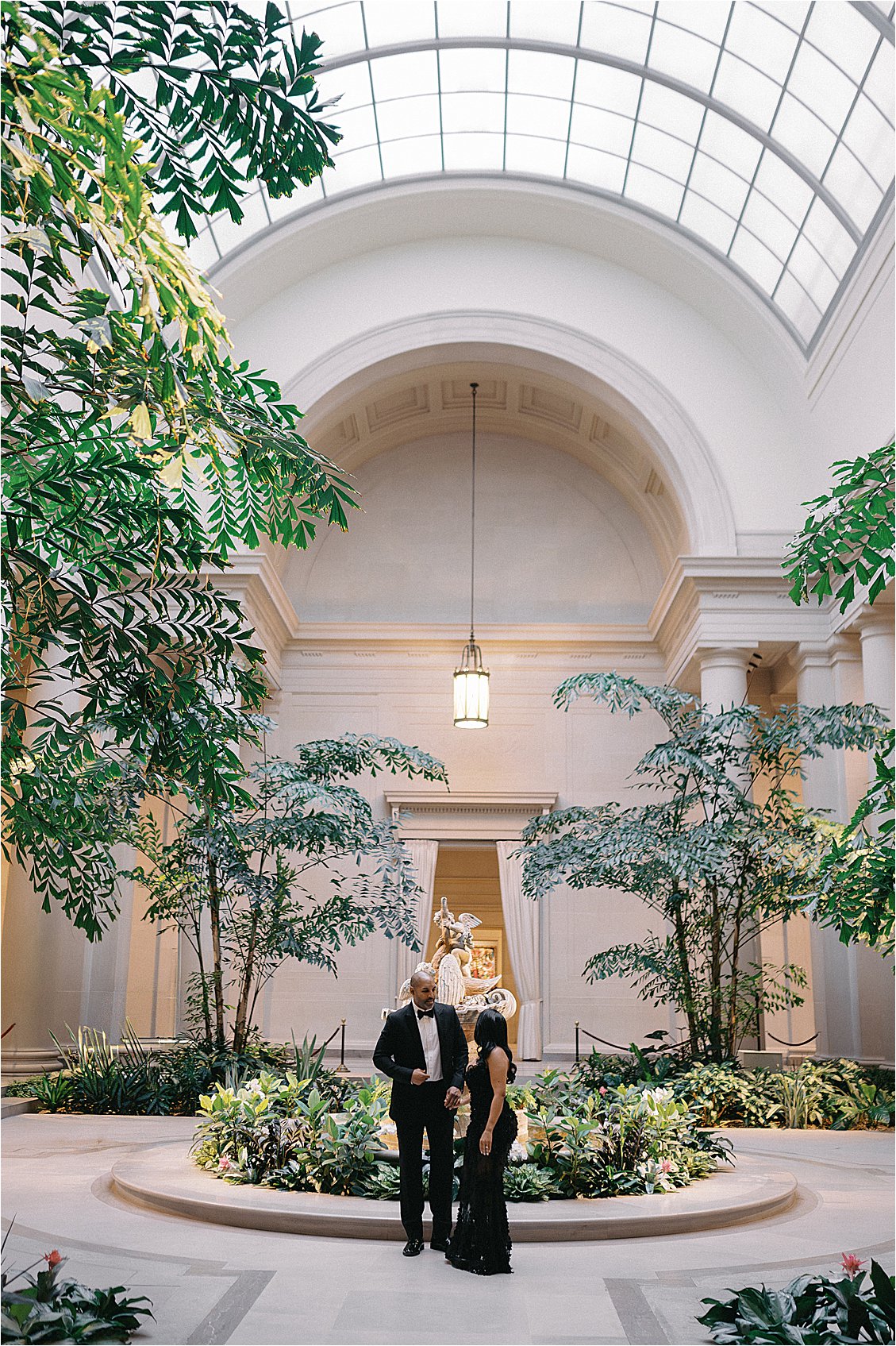 Engaged couple beneath a domed glass ceiling during their National Gallery of Art photos session. Photo by destination film wedding photographer Renee Hollingshead.